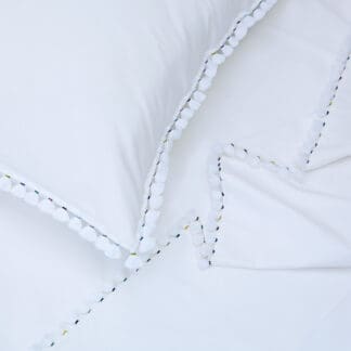white bed linen with embroidered pompoms