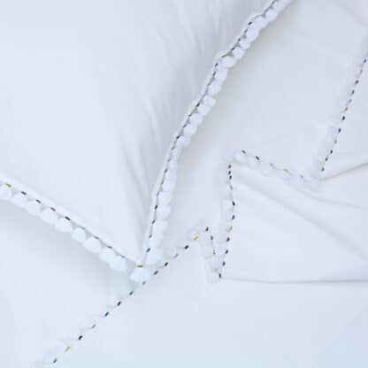 white bed linen with embroidered pompoms
