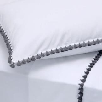 White bed linen with grey pompoms handmade in Marrakesh