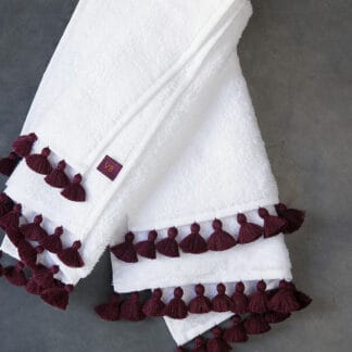 white bath linen with plum pompoms