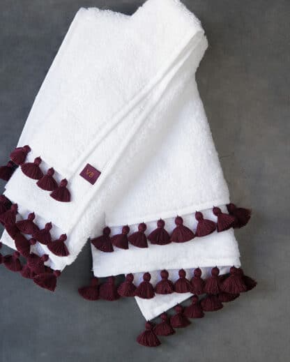 white bath linen with plum pompoms